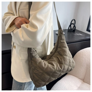 Close-up of army green quilted nylon crossbody bag with diamond patterns on a model