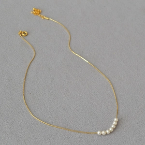 Detail view of seven round pearls on a minimalist 14k gold plated brass collar necklace