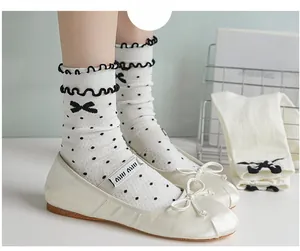 Detail of white cotton crew socks with black ruffled edge and bow pattern