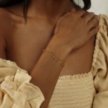 Gros plan d'un bracelet double chaîne plaqué or porté au poignet sous une lumière naturelle