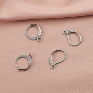Close-up of four silver stainless steel hoop earring findings on pink silk fabric
