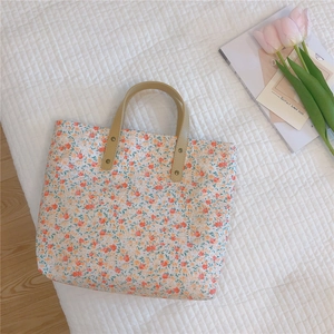 Close-up of floral tote bag with brown leather handles and reinforced metal rivets