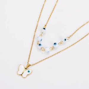 Detail of double-layer gold necklace featuring blue eye beads and a white butterfly pendant