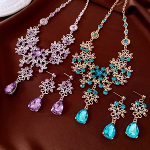 Detailed view of floral jewelry sets with purple and teal gems on dark silk