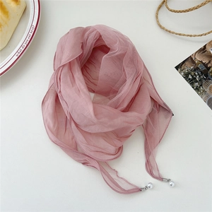 Detailed view of pink lace scarf with delicate pearl pendants on a white background