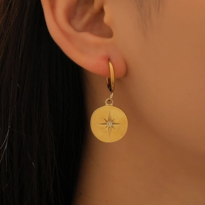 Gros plan de boucles d'oreilles dorées avec motif d'étoile et un petit diamant