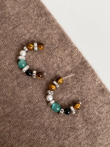 Detail of C-shaped hoop earrings featuring tiger eye stone and multi-colored beads