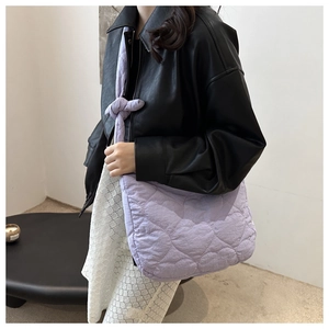Detail of the purple heart-quilted tote bag featuring a decorative knot on the shoulder strap
