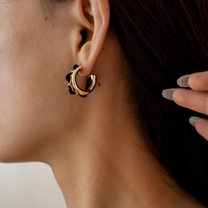 Détail de boucles d'oreilles en C dorées avec tissu noir portées par un mannequin