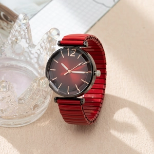 Detail of red gradient watch dial with rose gold markers and elastic metal band