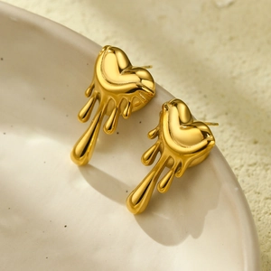 Macro detail of golden lava heart earrings on a ceramic dish with modern fluid design