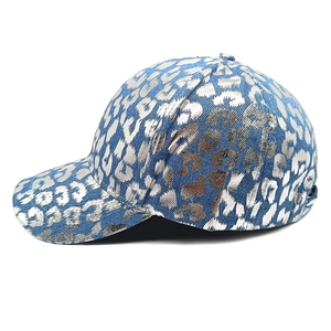 Detail of blue denim baseball cap with silver metallic leopard print pattern and stitching