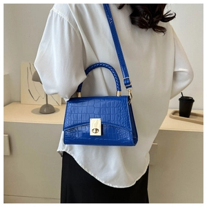 Blue crocodile pattern crossbody bag with gold lock shown on a model's back
