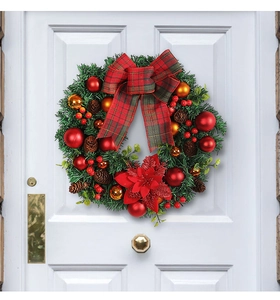 Detailed Christmas wreath featuring red bows and pine cones on a white door