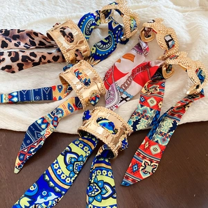 Detail of elegant gold hollow buckles with colorful silk-like printed fabric scarf wraps
