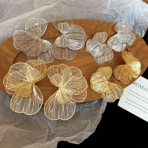 Gros plan de boucles d'oreilles fleurs en maille dorée et argentée avec pétales superposés