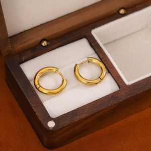 Golden stainless steel hoop earrings presented in a wooden jewelry storage box