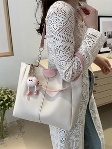 Borsa tote beige minimalista con manici rosa e ciondolo di peluche su una modella