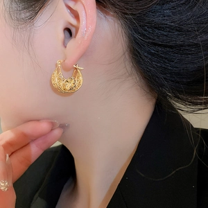 Macro shot of gold-plated cutout flower hoop earrings worn on a model in vintage style