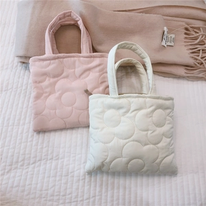 Dettaglio di mini borse shopper trapuntate a fiori in rosa e bianco con texture soffice