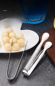 Close-up of 410 stainless steel sugar tongs on a stone surface with kitchenware