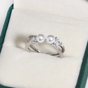 Detail of silver double pearl ring with zircon heart accents in a green velvet gift box