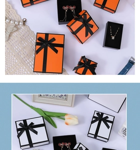 Detailed top view of orange jewelry gift boxes with black ribbons and velvet lining inserts