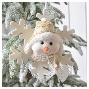 Close-up of plush snowman and felt snowflake ornament hanging on a snowy Christmas tree
