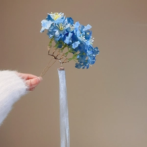 Detail of light blue fabric flower hair pin with long flowing silk ribbon tassels