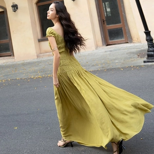 Détail d'une robe longue vert olive avec taille plissée et tissu texturé fluide