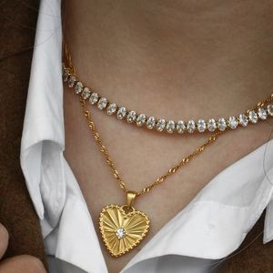 Dettaglio della collana a strati con pendente a cuore dorato e catena di zirconi