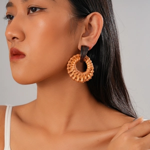 Detail of bohemian round rattan woven earring worn by model with natural wood texture