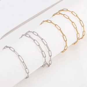 Gold and silver paperclip link jewelry set with textured finish on white display