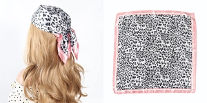 Detailed view of leopard print square silk scarf with a vibrant pink border edge