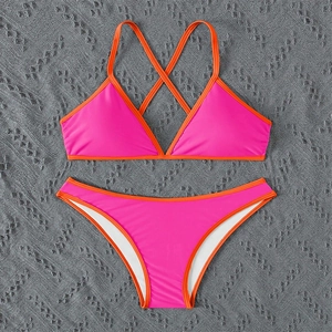 Detailed top view of a vibrant hot pink and orange color-block bikini set on textured mat