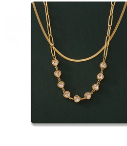 Detail of double-layer gold snake chain and paperclip link necklace with heart zircons