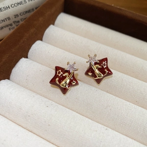 Macro shot of 18k gold plated star stud earrings with burgundy enamel and cat motif
