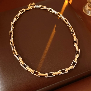 Detail of adjustable chain necklace in gold and silver tones on a brown leather surface