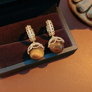 Detailed view of vintage gold-plated tiger eye earrings with cubic zirconia on black velvet