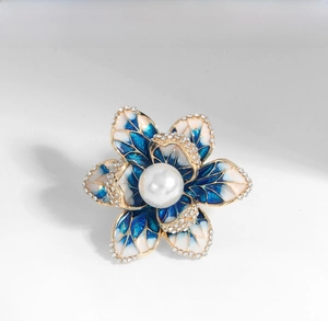 Detail of blue and white enamel flower brooch with rhinestones and center pearl inlay