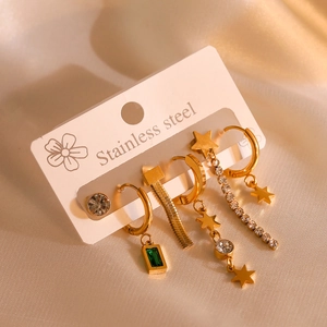 Detailed close-up of gold stainless steel earrings with zircon and green gemstone pendants