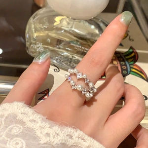 Elegante anello aperto a doppio strato con perle e zirconi sul dito di una modella