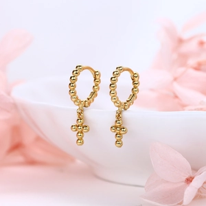 Macro detail of gold S925 sterling silver hoop earrings with beaded cross pendants