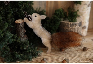Detailed view of foam squirrel decoration holding pinecone in a forest scene setup