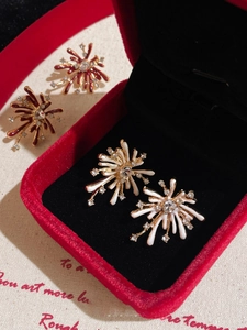 Detail view of sparkling firework stud earrings with rhinestones in a red velvet jewelry box