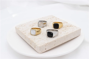 Detail of minimalist gold and silver shell inlay rings on a natural stone tray