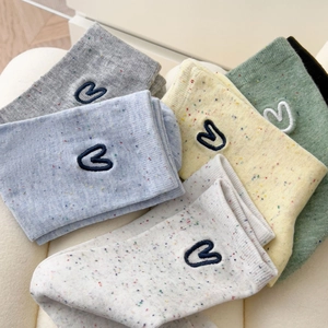 Close-up of colorful flecked socks featuring blue embroidered heart detail on ribbed cuffs