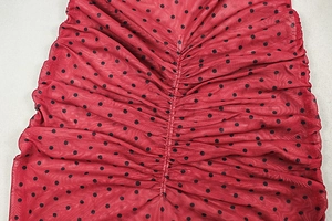 Detail of red mesh fabric with black polka dots featuring vertical pleated design