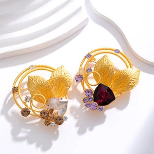 Vintage gold leaf crystal brooches with champagne and purple gemstones on white background