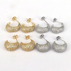 Macro shot of gold and silver C-shaped earrings with full pave setting and clear cubic zirconia